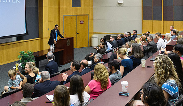 man at podium in crowded conference room