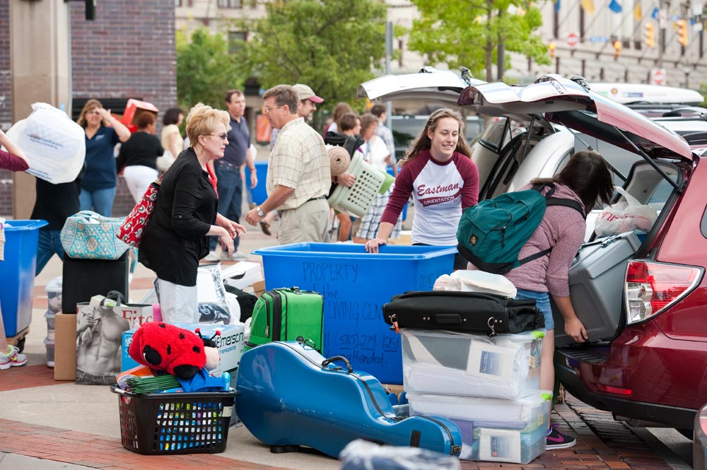 large crowd of students and families unload cars