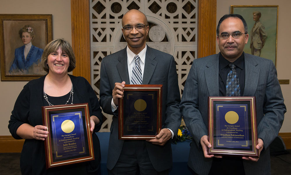 Feature image a woman and two men, holding plaques