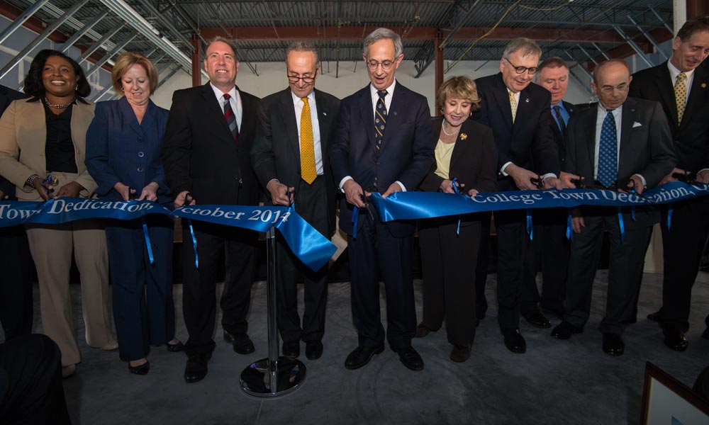 large group of officials and leaders cutting the ribbon for College Town