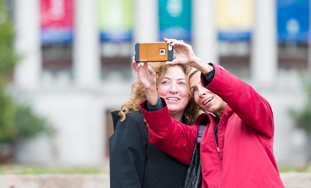 Feature image two women taking selfies by library