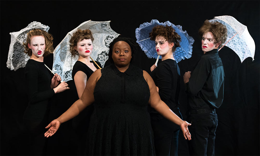 Feature image actors in black, some in whiteface with white parasols