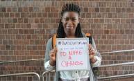 woman holds sign that reads I Turn Out to Vote To Make a Change