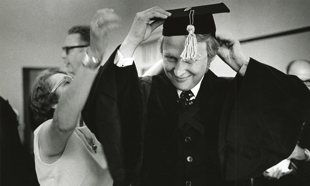 Feature image archival photo of Mike Nichols adjusting his commencement cap before the ceremony