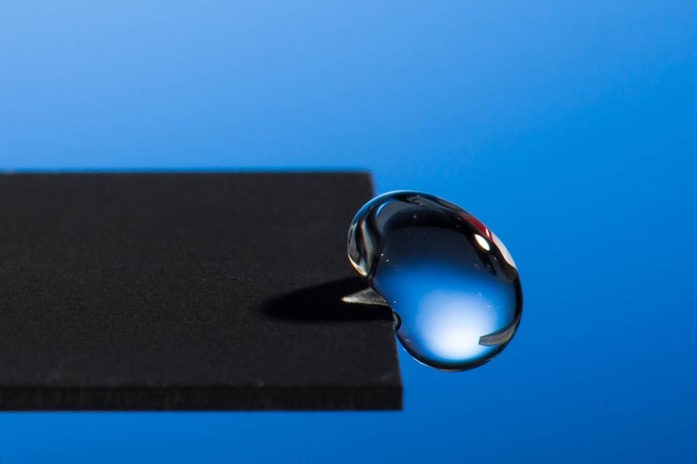 Feature image photo of a droplet of liquid hanging off the edge of a surface