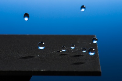 professor Chunlei Guo has developed a technique that uses lasers to render materials hydrophobic, illustrated in these images of water droplets bouncing off a treated sample. // photo by J. Adam Fenster / University of Rochester