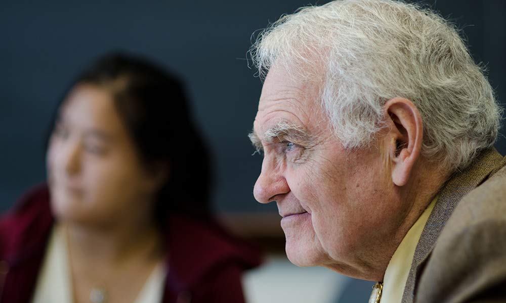 profile view of Russell Peck with a student in the background.