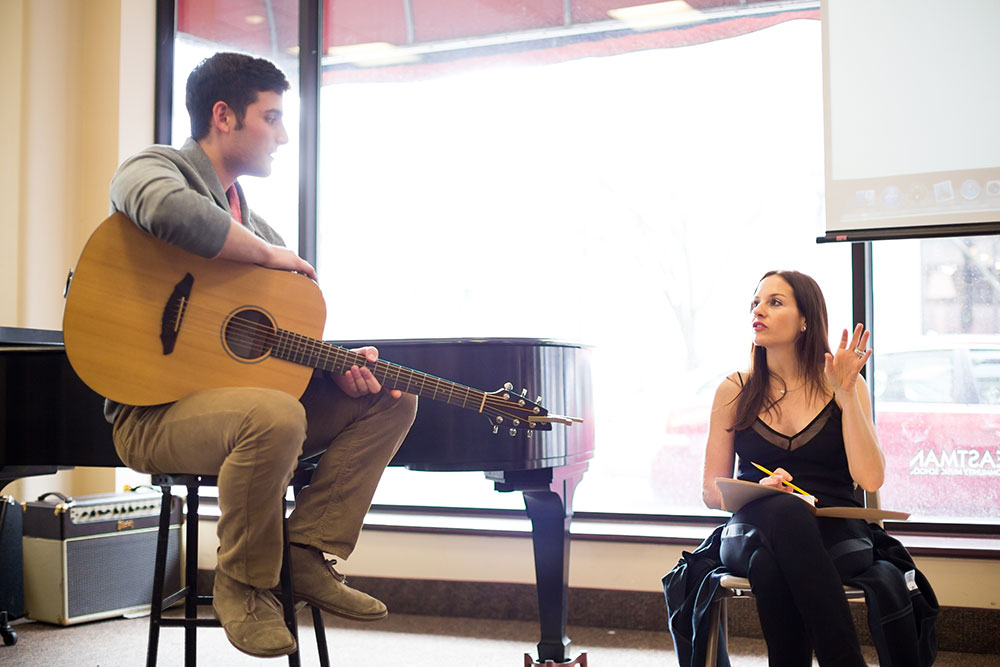 Feature image student playing guitar as instructor listens