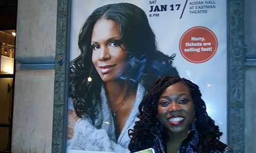 Feature image student posing with poster of Audra McDonald outside theater