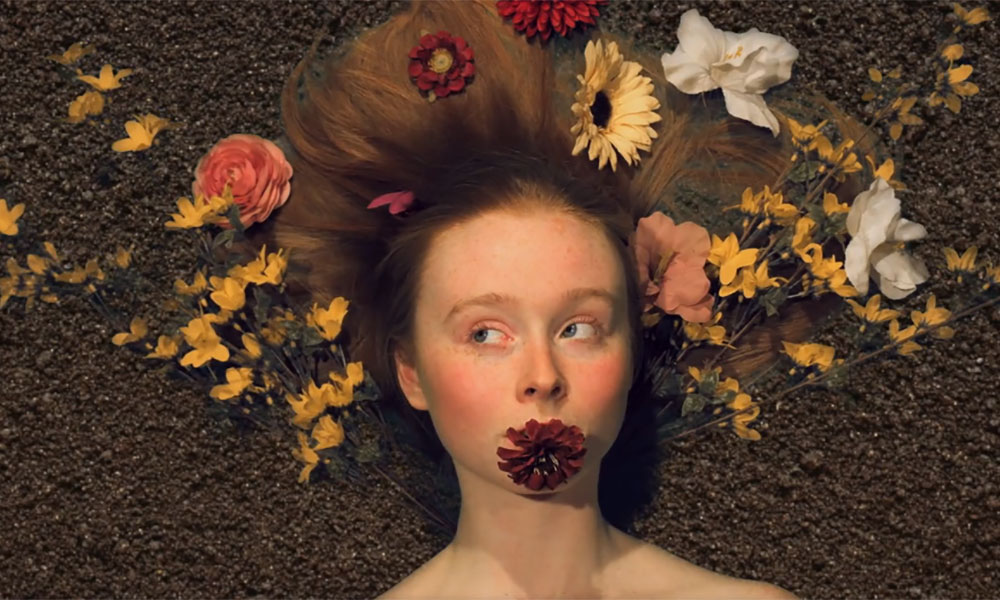 Feature image screenshot from film features closeup of woman with flowers in her hair
