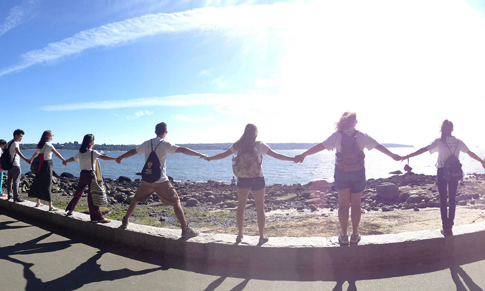 Feature image group of students holding hands and looking out over the water