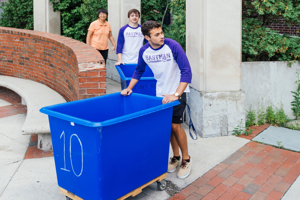 Eastman student wheels large empty bin.