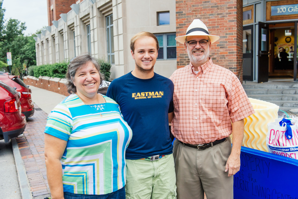 student in Eastman School t-shirt poses with parents