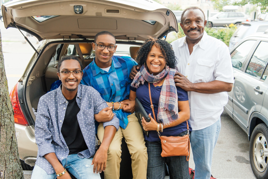 family poses outside their car after moving in