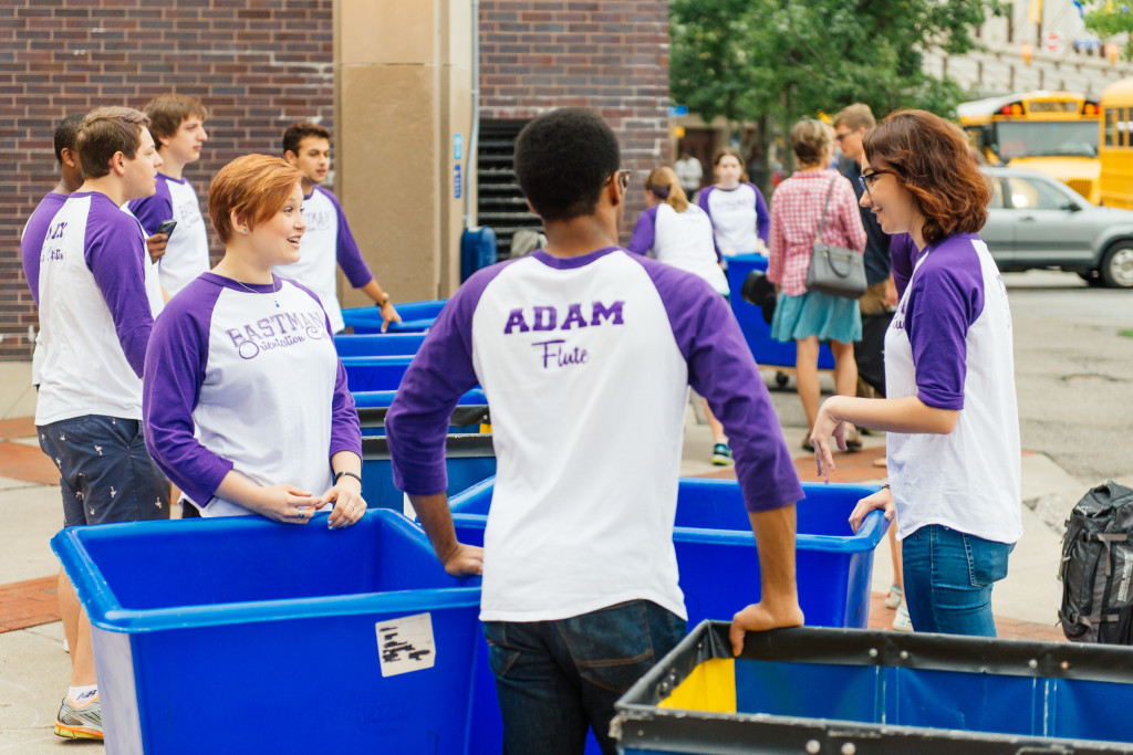 students in matching t-shirts help others move belongings