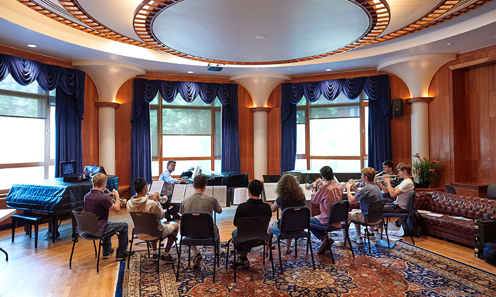 Feature image groups of student trumpet players sitting in a circle around instructor