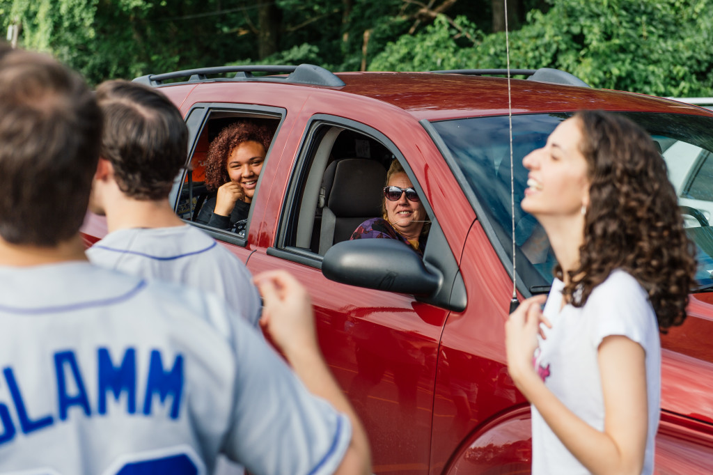 students in cars listen to a cappella group perform