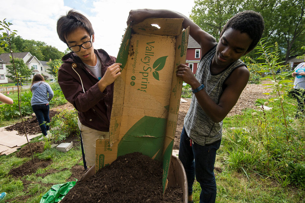 students empty mulch into wheelbarrow