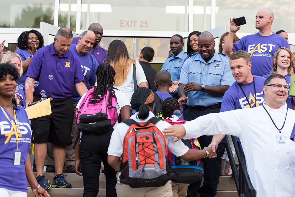 teachers high-five students as they walk into building