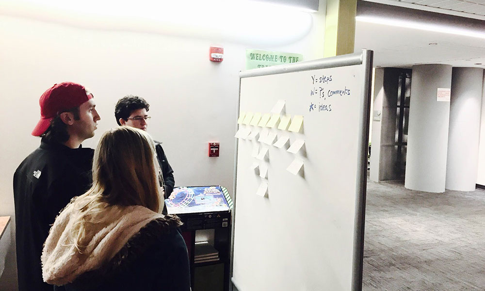 Feature image three students standing in front of a white board