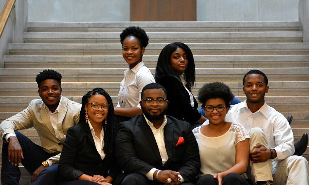 Feature image group of students pose for a portrait on library steps.