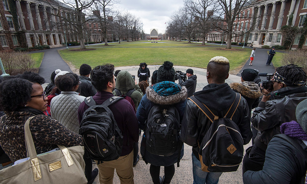 Feature image students gather on library steps as one reads a statement