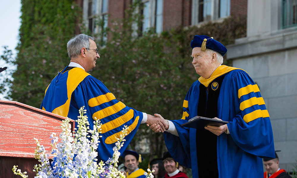 Feature image Joseph Cunningham and Joel Seligman shaking hands at commencement