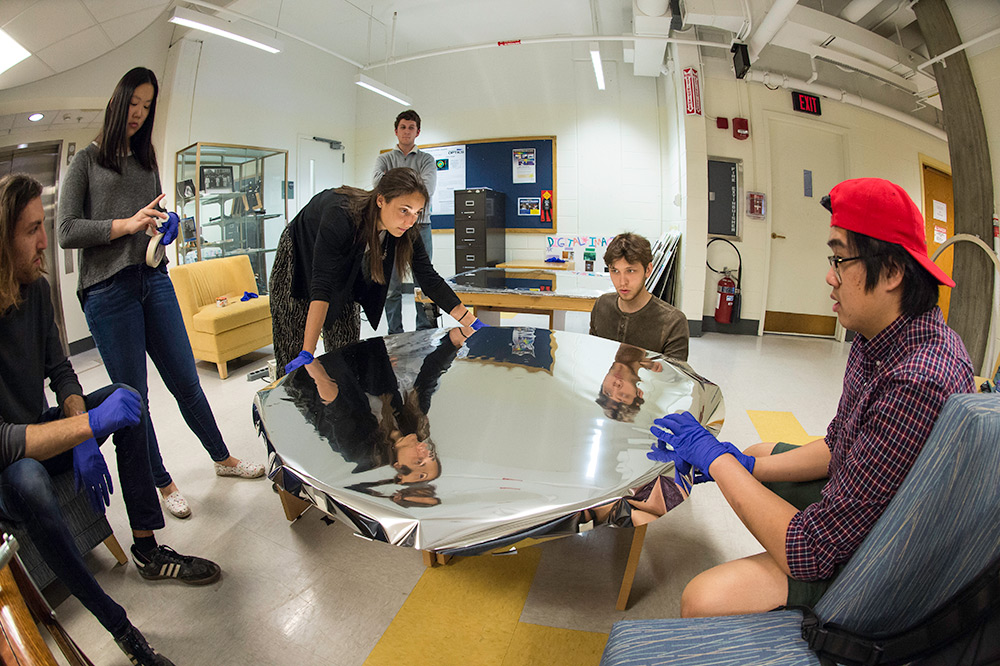 group of students with large circular solar mirror