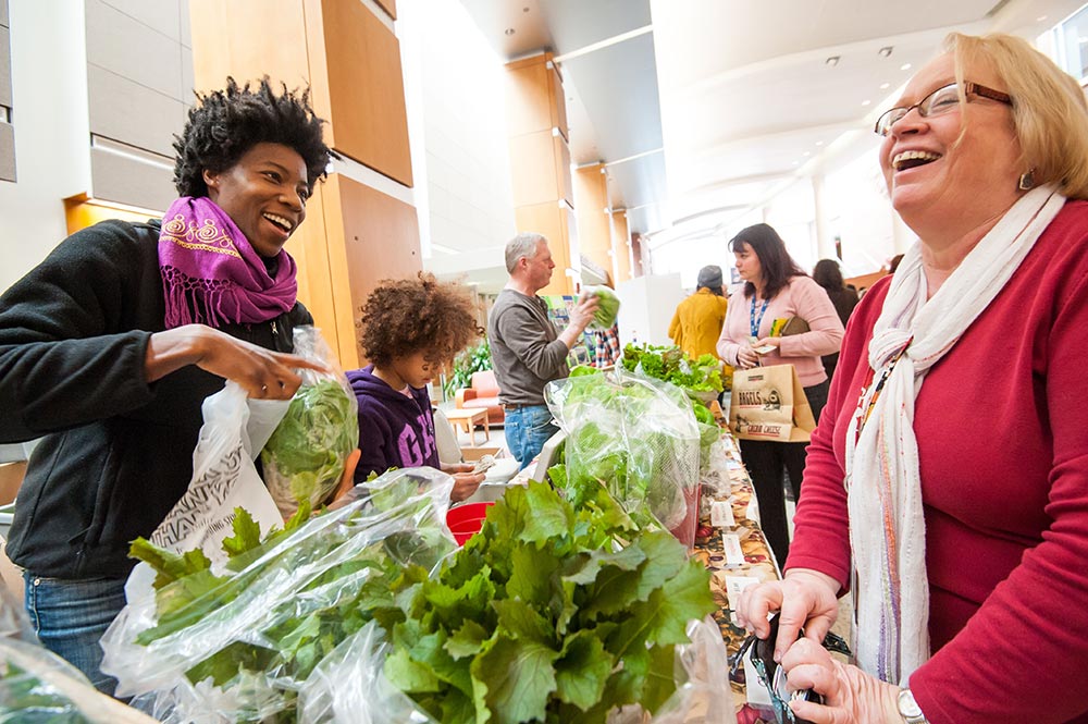 farmers market customer receives vegetables from vendor