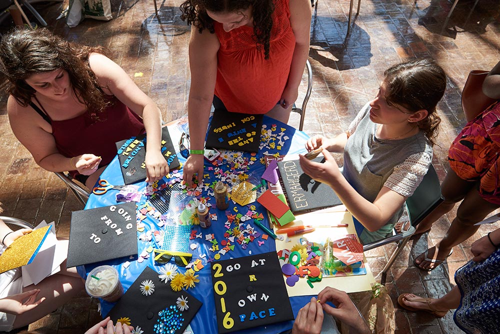 Feature image group of students at a table with supplies for decorating graduation caps