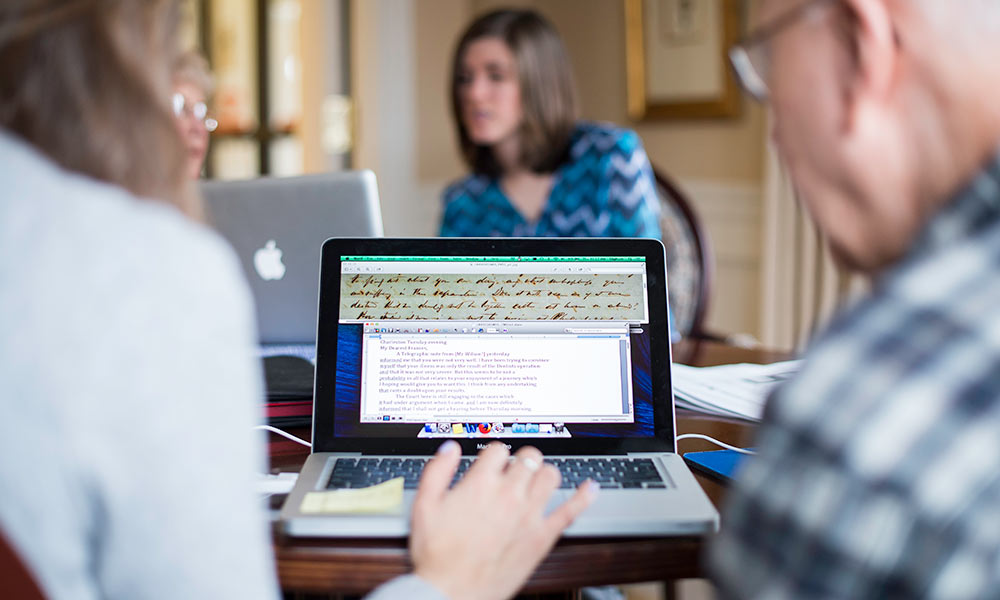 Feature image photo of students and older volunteers at a laptop