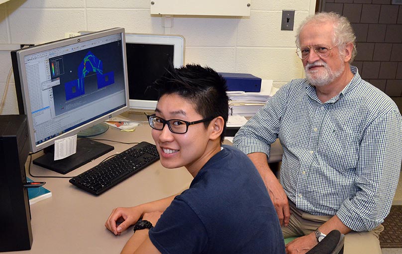 student with professor in front of computer