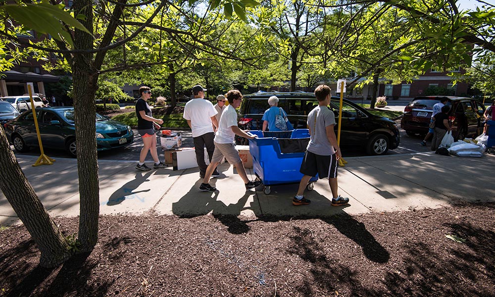 Feature image families push carts full of stuff to the residence halls