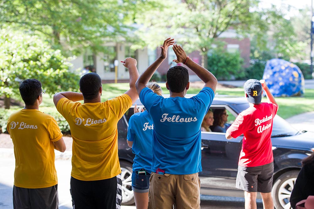 student in matching t-shirts applauding the arrival of cars in front of Susan B. Anthony Halls