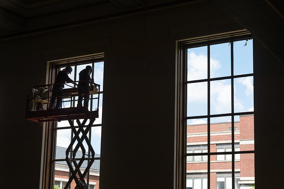 workers on a construction lift in front of large windows in Strong Auditorium