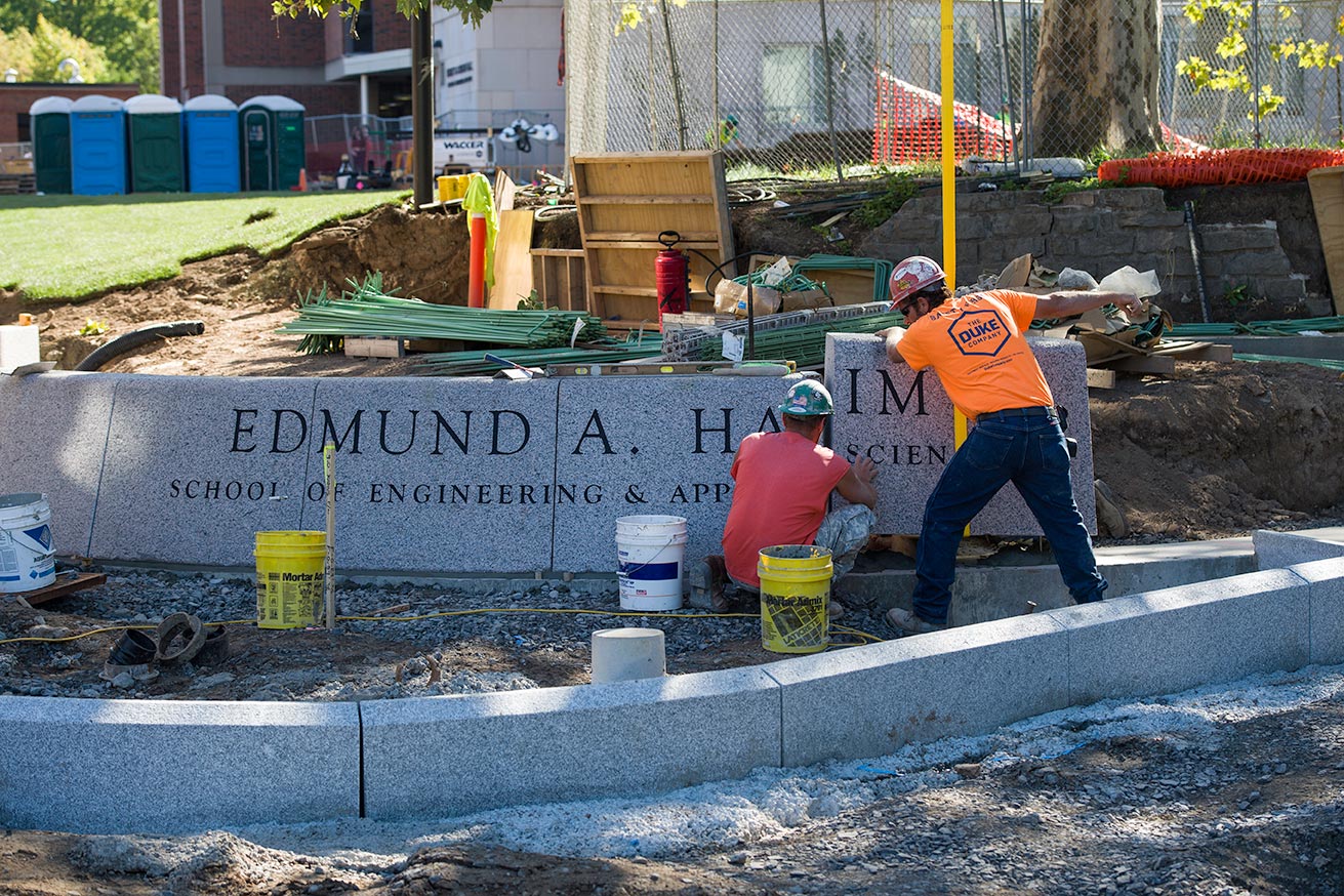 Feature image workers lower a piece of a granite sign into place; sign reads EDMUND A. HAJIM SCHOOL OF ENGINEERING AND APPLIED SCIENCES
