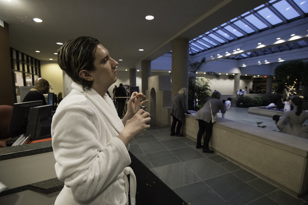 student in white robe posing with hands in front