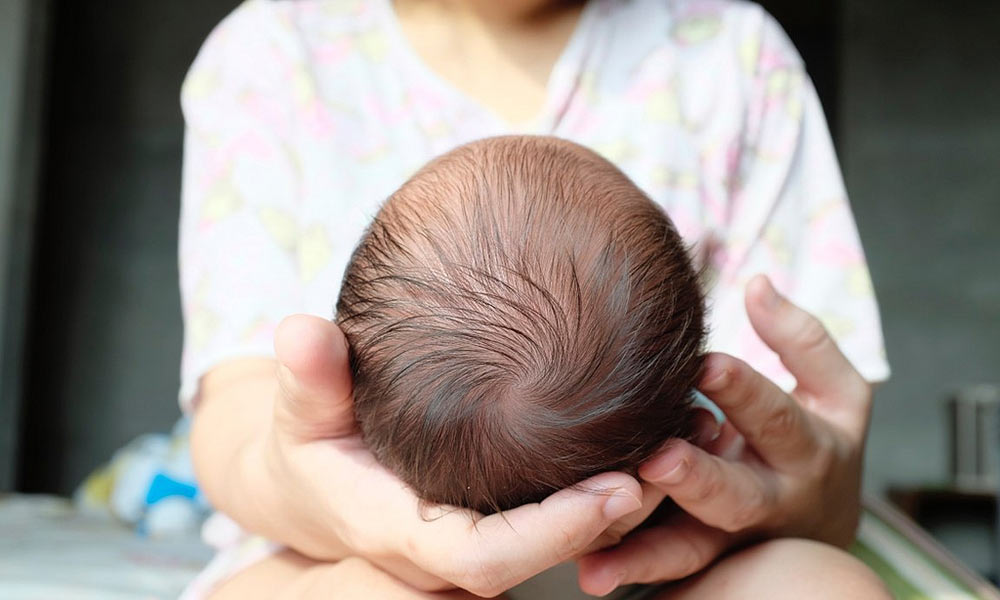 Feature image back of baby's head, as baby is held in mother's lap