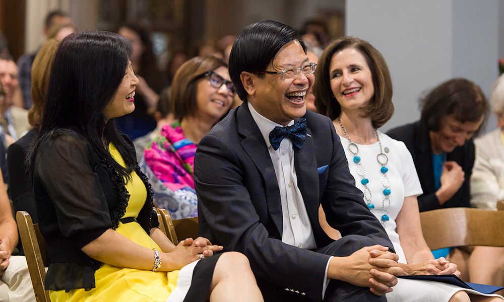 Feature image Susana Lam, Evans Lam, and Mary Ann Mavrinac laugh from the audience during dedication ceremony