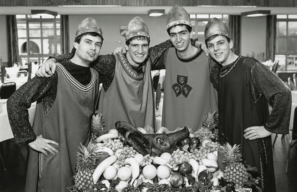 students in medieval dress with a boar's head on a platte