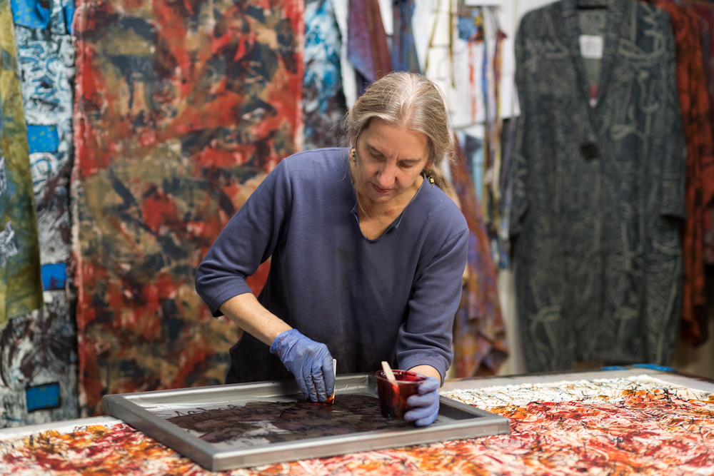 woman painting a screen on top of a table