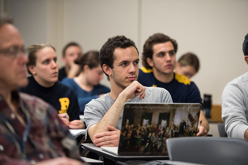 student with laptop decorated with painting of the Founding Fathers