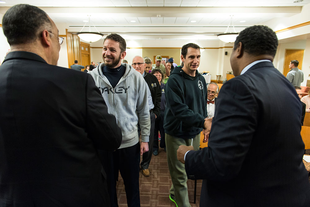 Feature image line of people receiving pins, shaking hands
