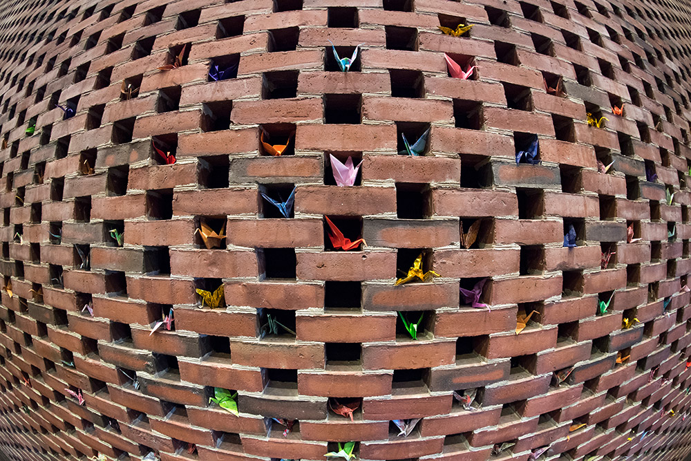 origami cranes folded into gaps in a wall