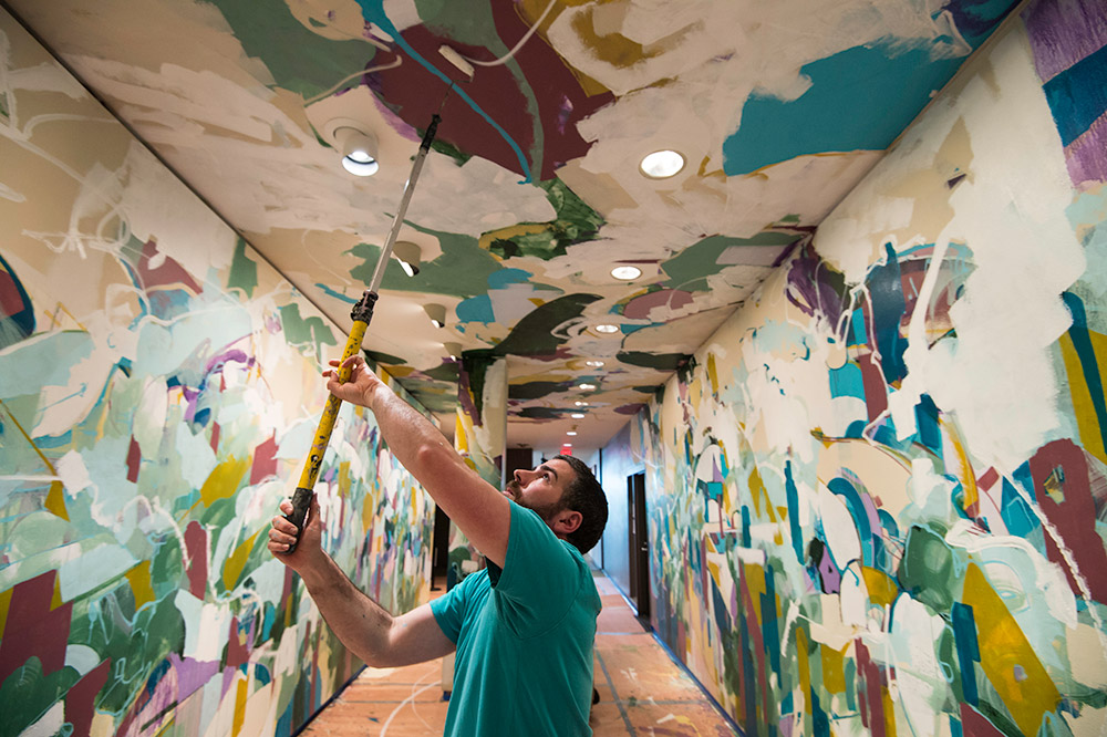 main painting ceiling with brush on a pole