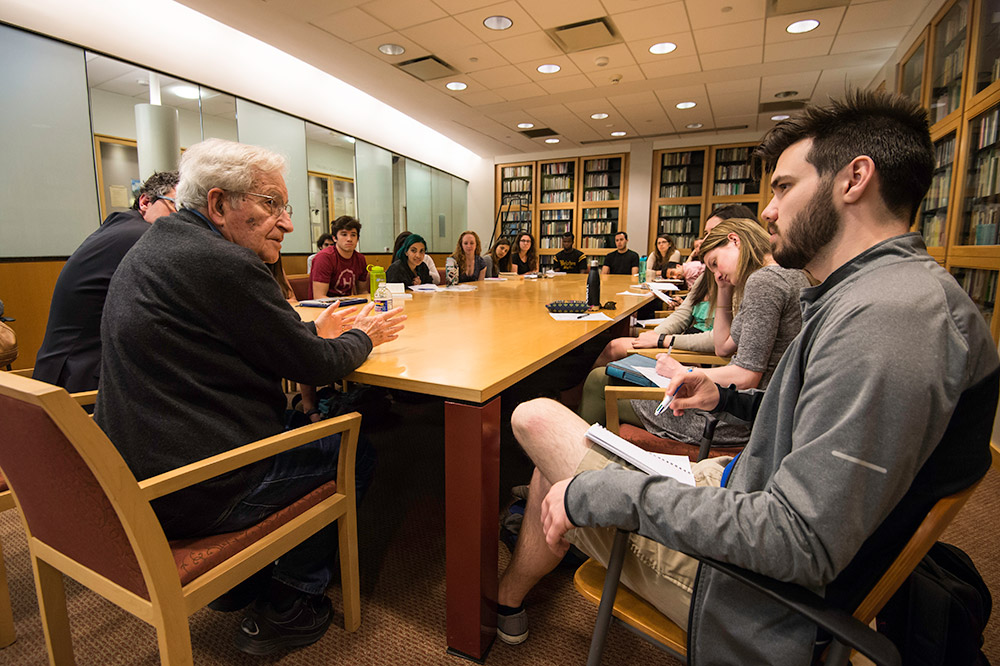 Noam Chomsky sitting at conference table with students