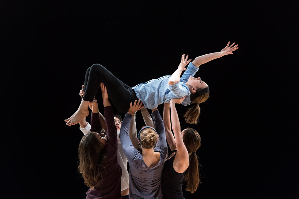 dancers holding another dancer aloft