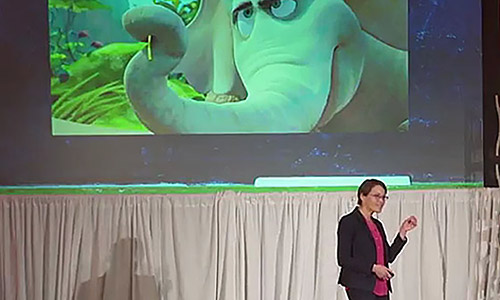 Feature image professor in front of screen with an image of an animated elephant