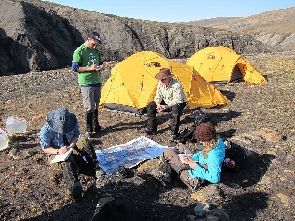 people taking notes near yellow tents on a barren campground