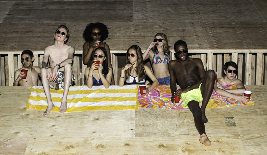 group of student actors lying on beach towels on a very steep stage